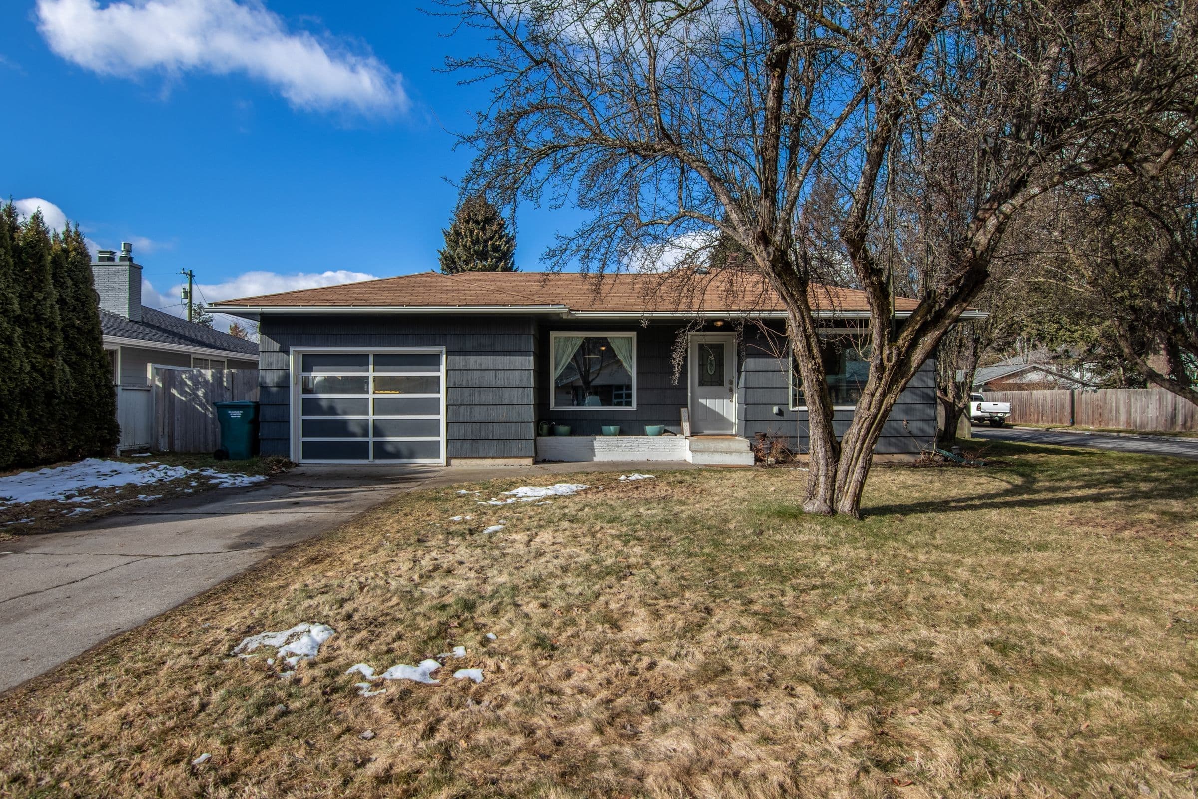 A ranch house with a big ash tree and leftover snow on the lawn near Crooks, where we do mobile windshield replacement